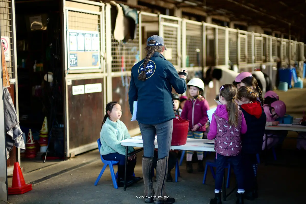 Child learning about horse tack and equipment at Eastside Riding Academy school holiday camp